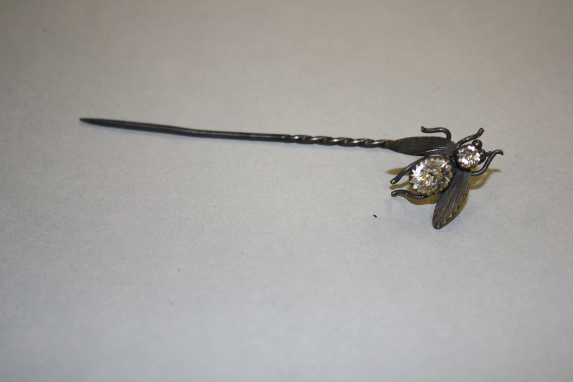 a single pin with a decorative fly like insect with a sparked body and head 