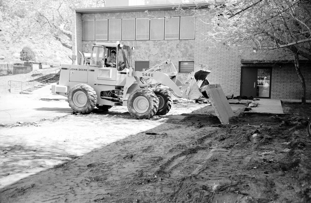 Man operating construction excavator during construction of headquarters addition.