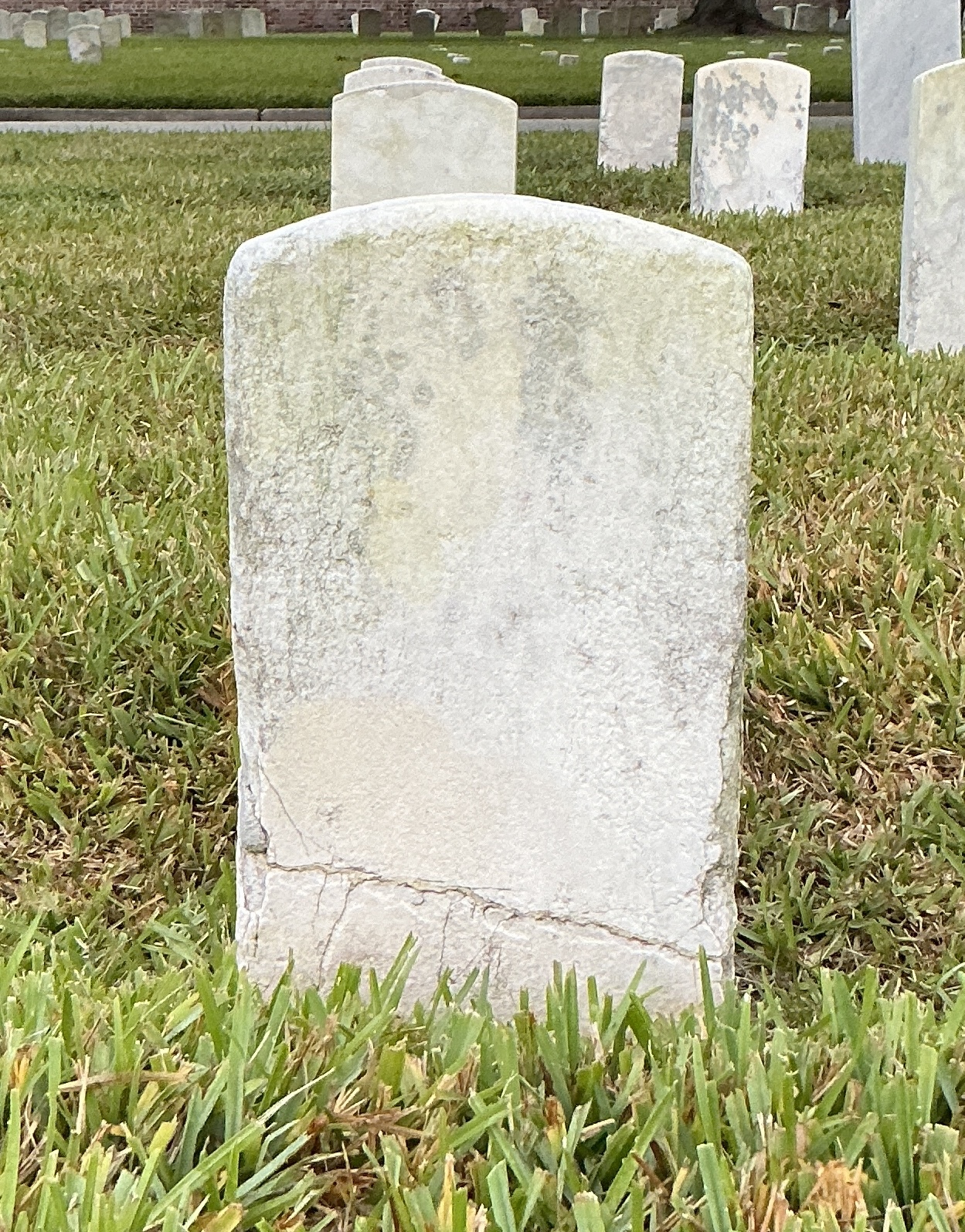 Back of historic upright marble headstone with recessed shield face.