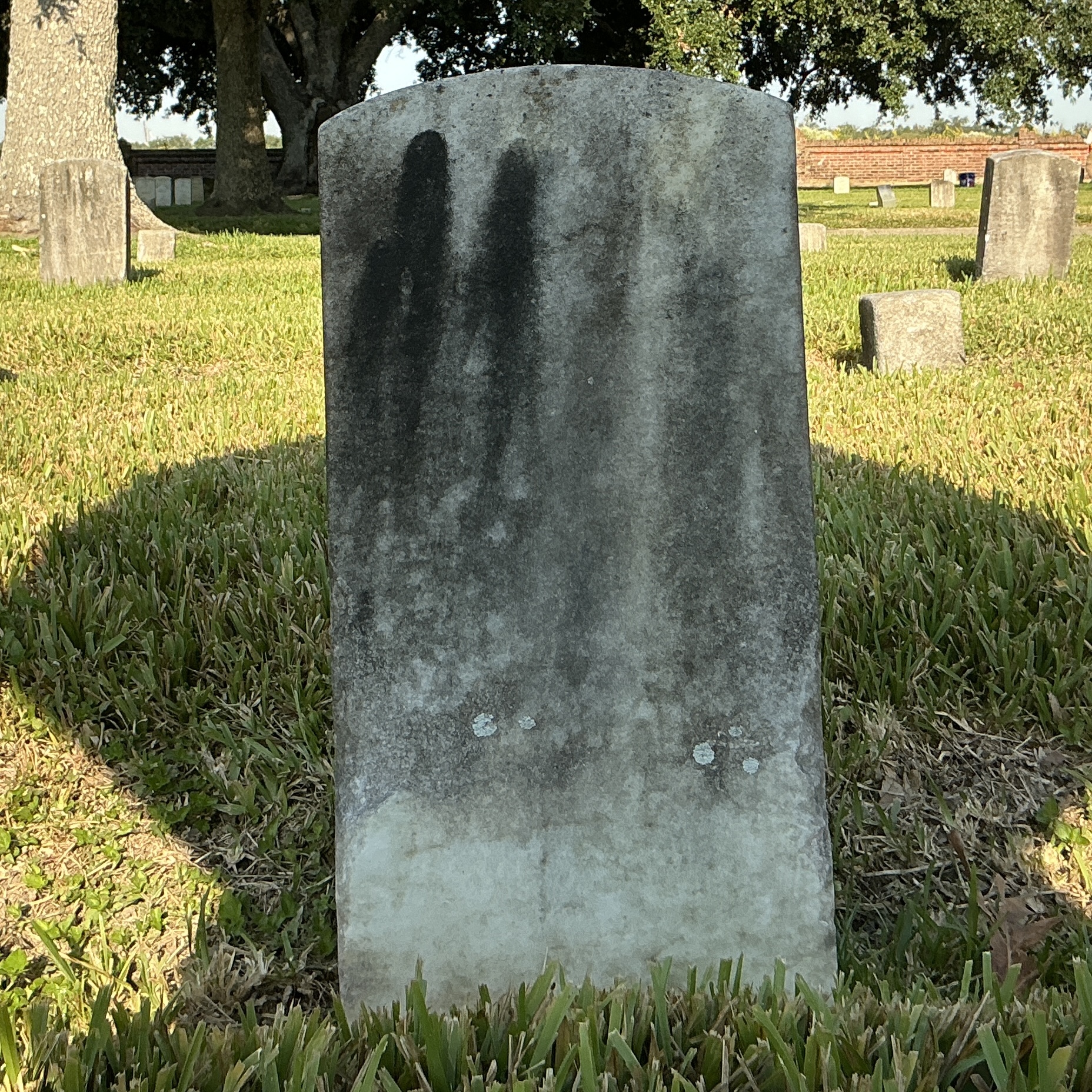 Back of historic upright marble headstone with recessed shield face.