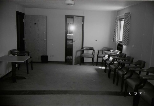 Chairs along wall of living room area in barracks. [Image possibly for comparative housing study]