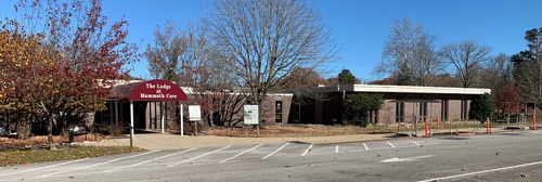 a.	A long single story brink building with a red awning that says “The Lodge at Mammoth Cave” under a blue sky.