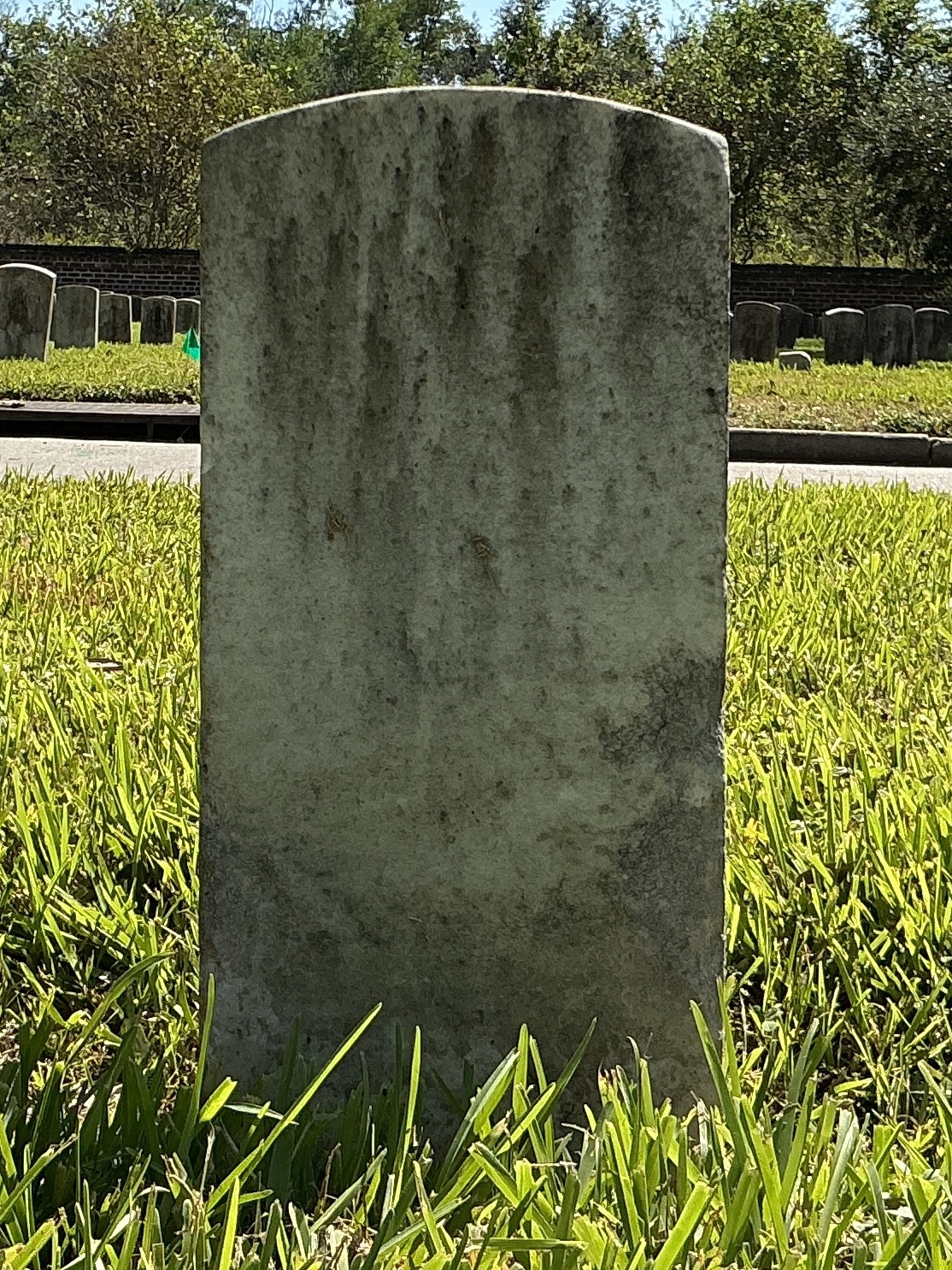 Back of historic upright marble headstone with recessed shield face.