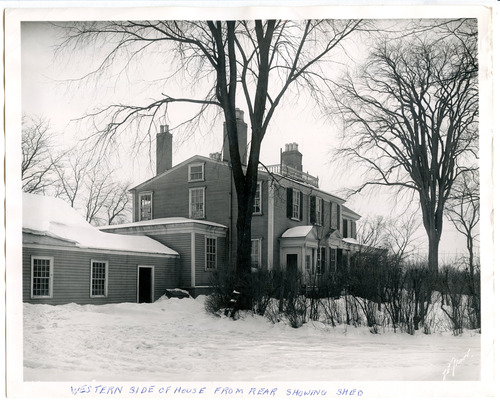 Black and white photograph of back of snow covered house.
