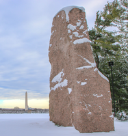 Granite monolith on a plaza after a snowfall with Washington Monument in the distrance