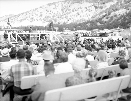 Warren F. Hamilton, Superintendent of Zion National Park, addressing visitors from podium at dedication of Taylor Creek road (Kolob Canyons). Note Hurricane Harmonetts [Harmonettes] singing group at right.