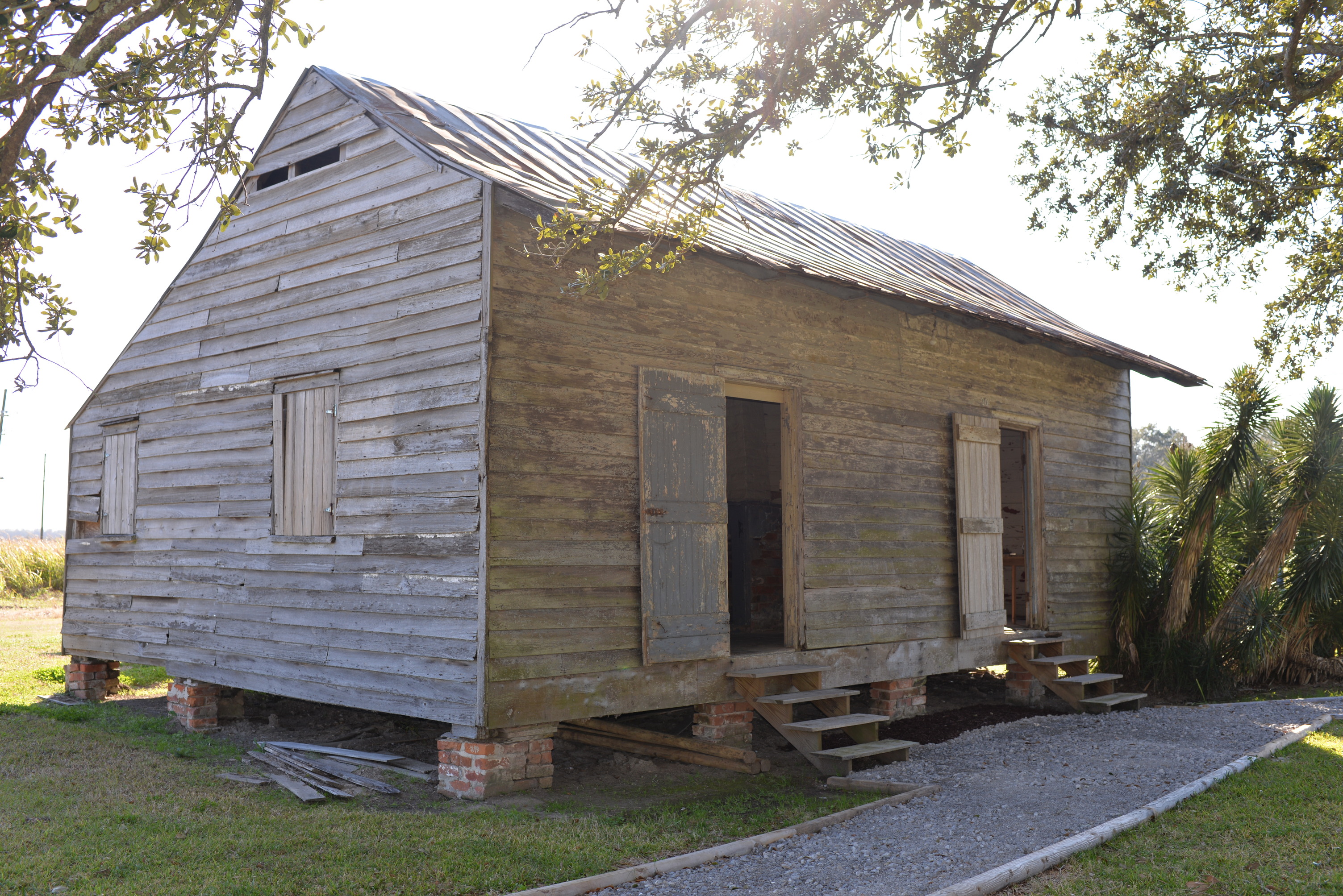 Wooden structure with two doors, short stairs leading to each, and a metal roof; it sits on short brick pillars.