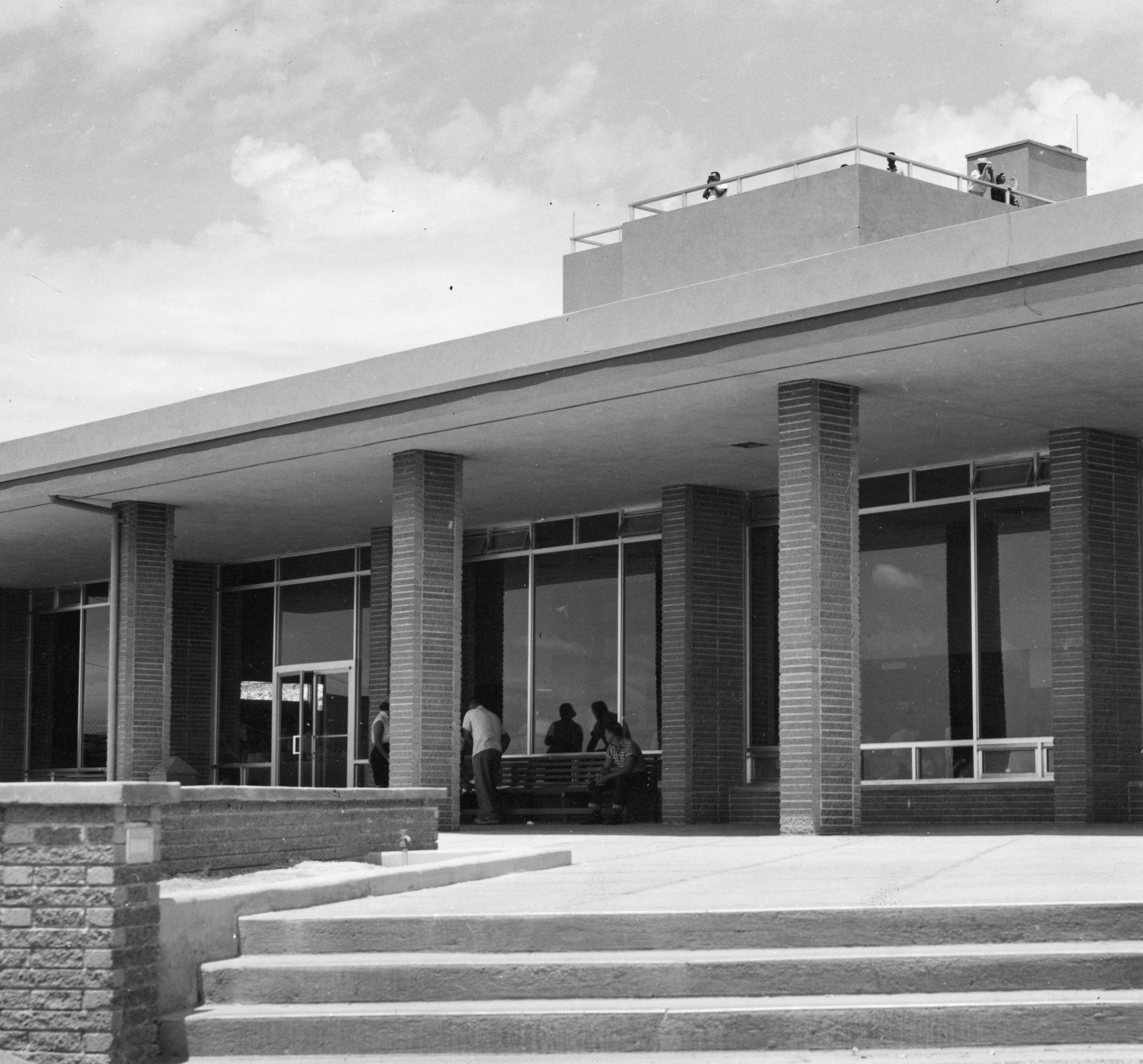 A black and white photograph of the exterior of the visitor's center. The overlook can be seen above the building.