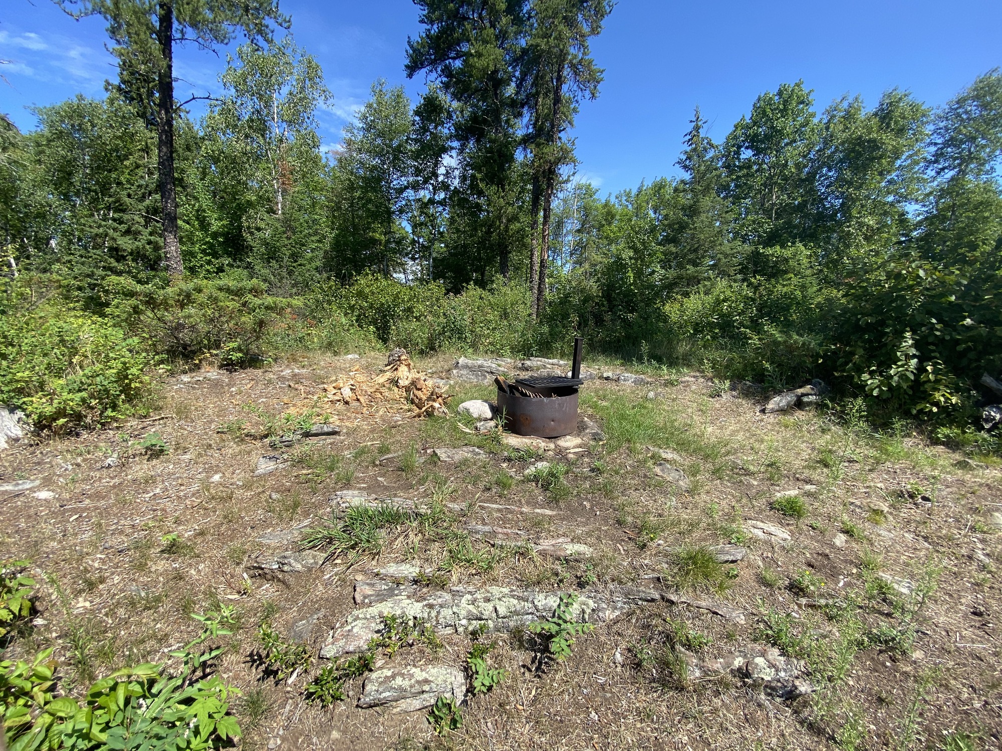 View looking into houseboat site core of rough rock terrain with the campfire ring in the middle. In the background are small shrubs and a few large trees.