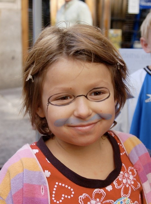 A young girl has her face painted to look like Theodore Roosevelt