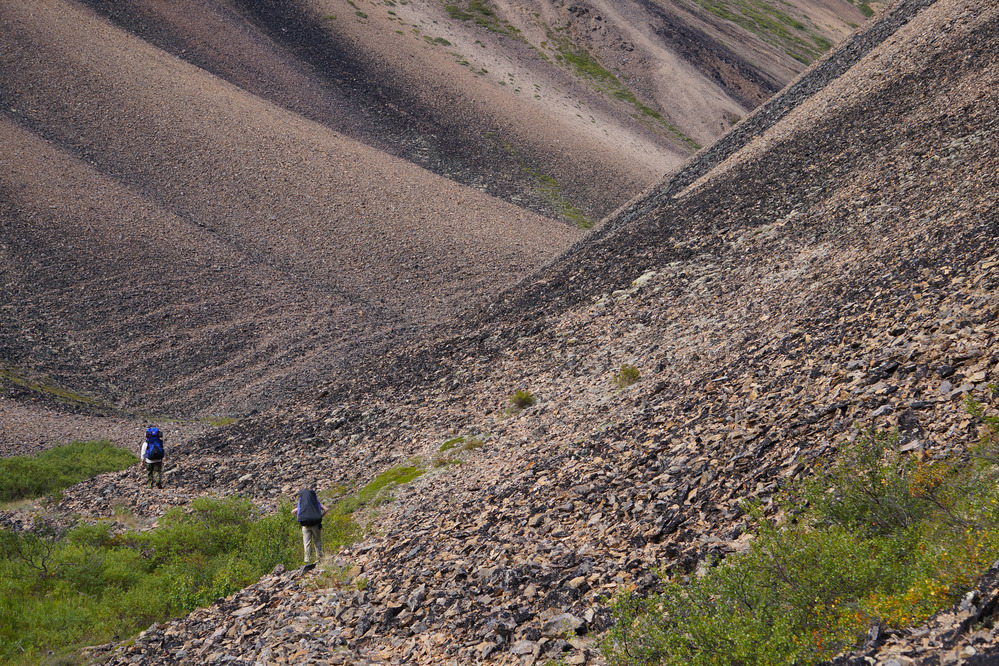 Hikers enter a narrow talus-filled valley.