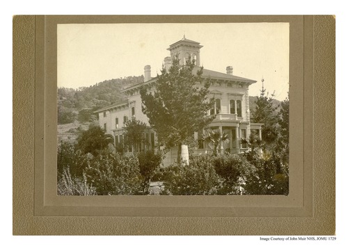 A historic photo of the two story Victorian Strentzel/Muir home, surrounded by trees. Hills can be seen in the background. 