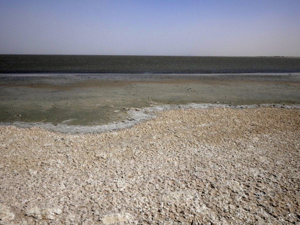 A body of water recedes leaving salt deposits behind