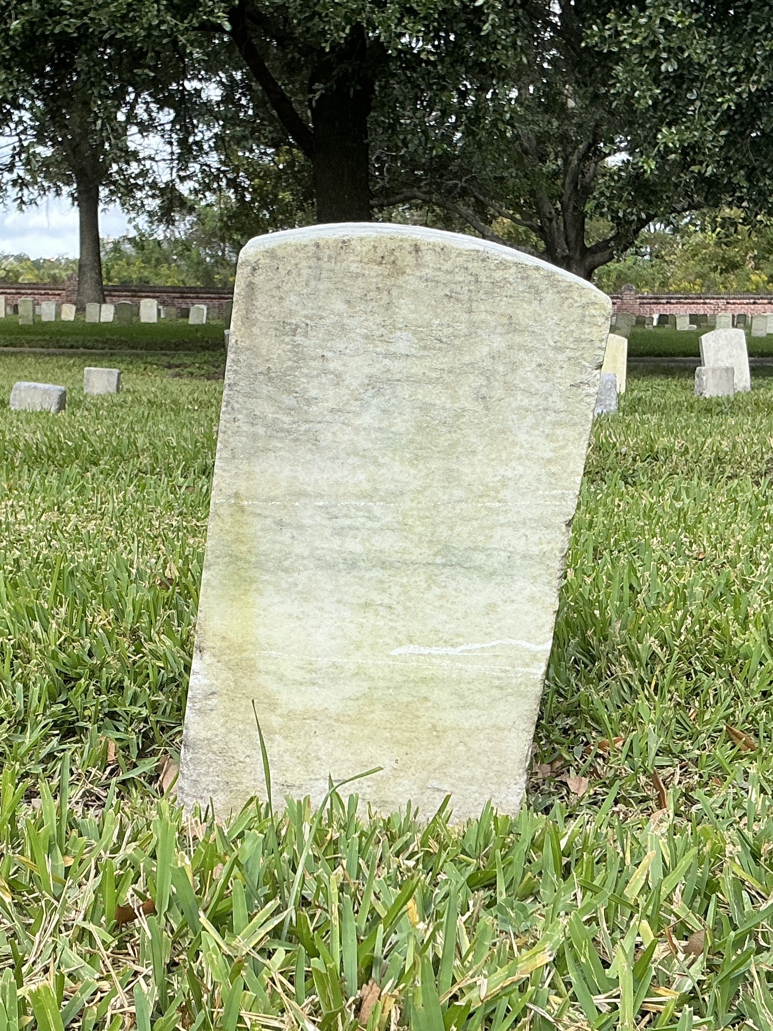 Back of historic upright marble headstone with recessed shield face.