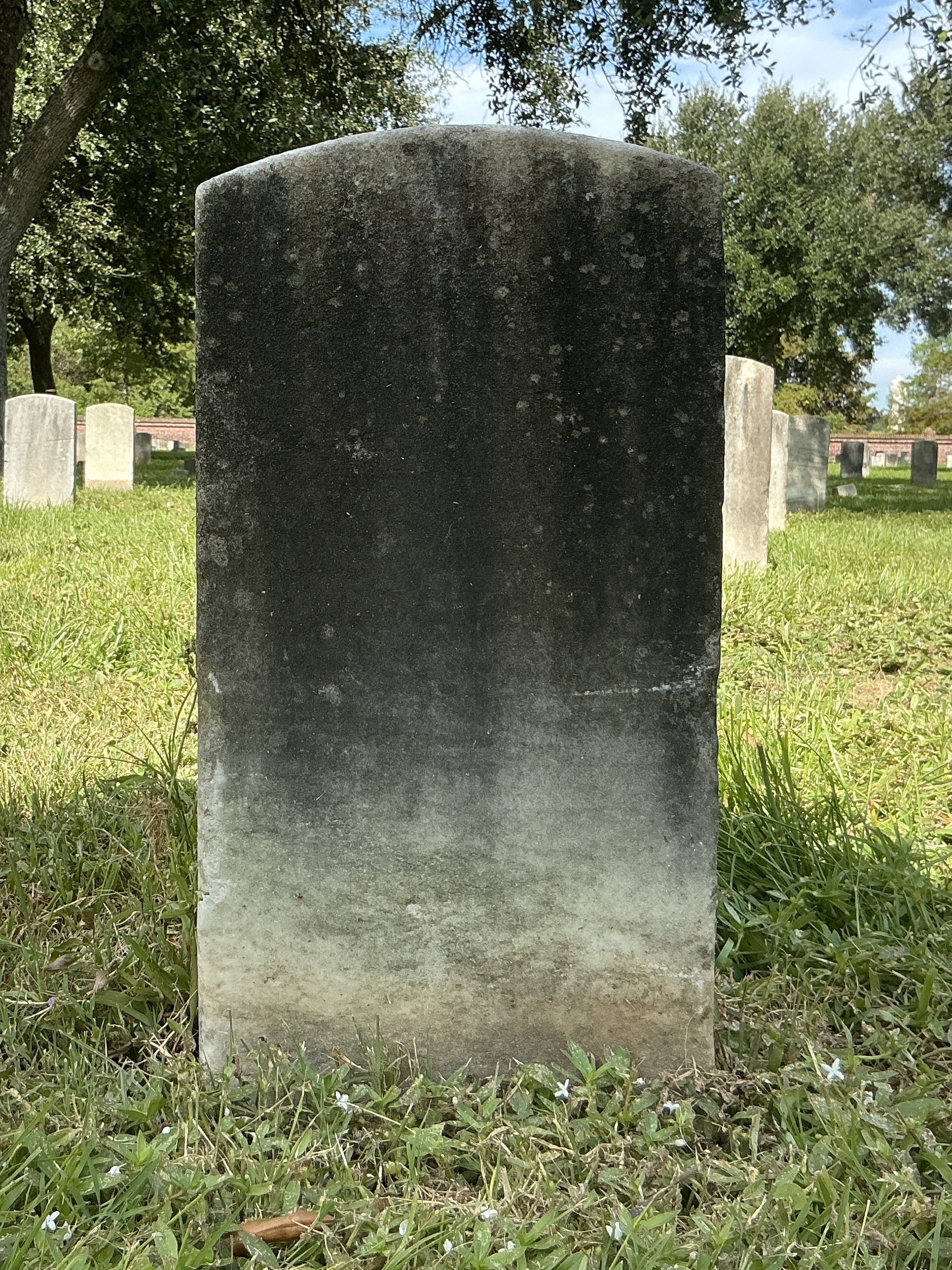 Back of historic upright marble headstone with recessed shield face.