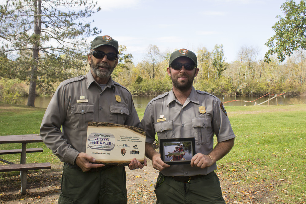 Two park rangers receiving recognition while standing near a landing. 