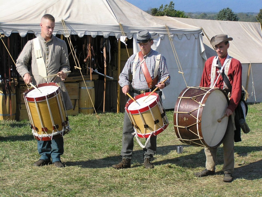 Three young drummers practice in camp.