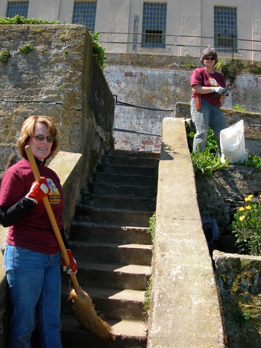 Volunteers help clean the areas surrounding the stairs and raised beds near the old Officer's Quarters.