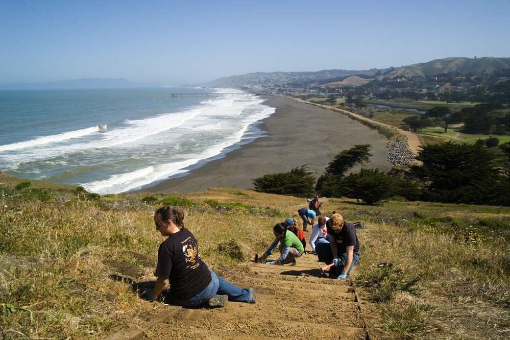 Scenic shot of Pacifica with the volunteers in the foreground weeding one of the staircases at Mori Point.