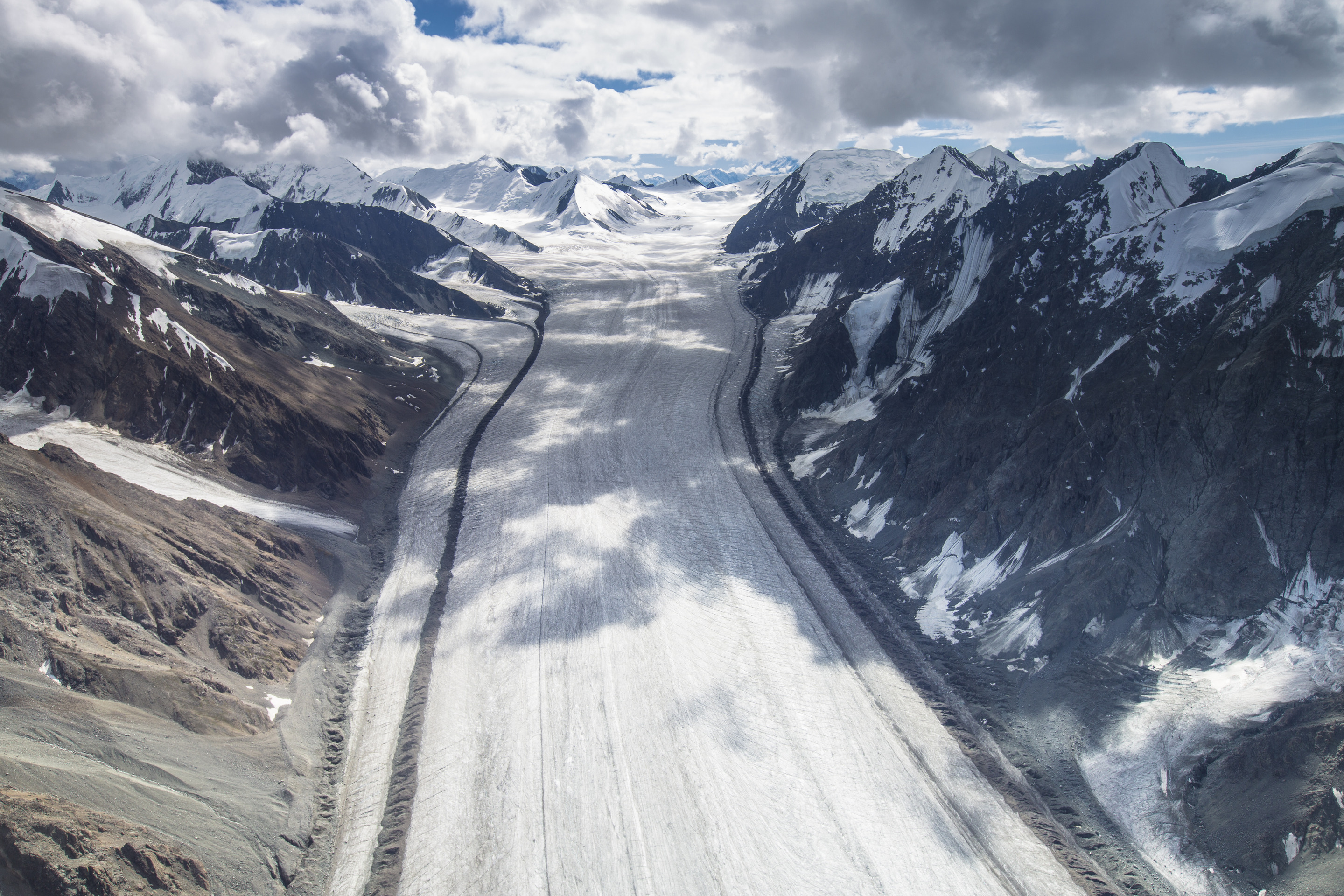 a straight sheet of ice runs down a valley surrounded by jagged snowy peaks 