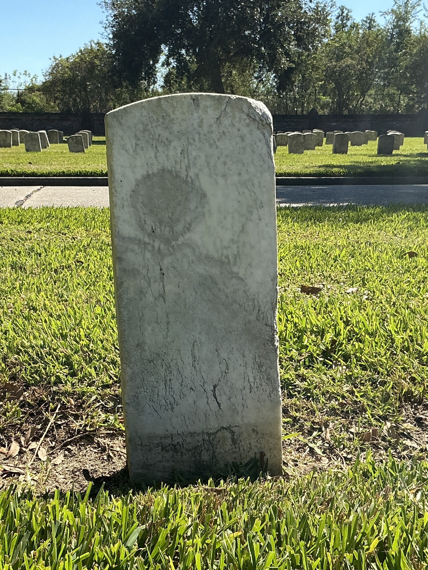 Back of historic upright marble headstone with recessed shield with recessed lettering face.