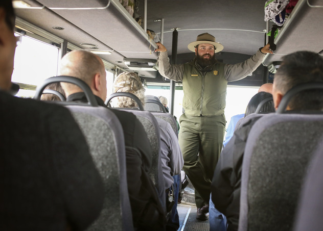 a park ranger standing on a bus speaking to passengers