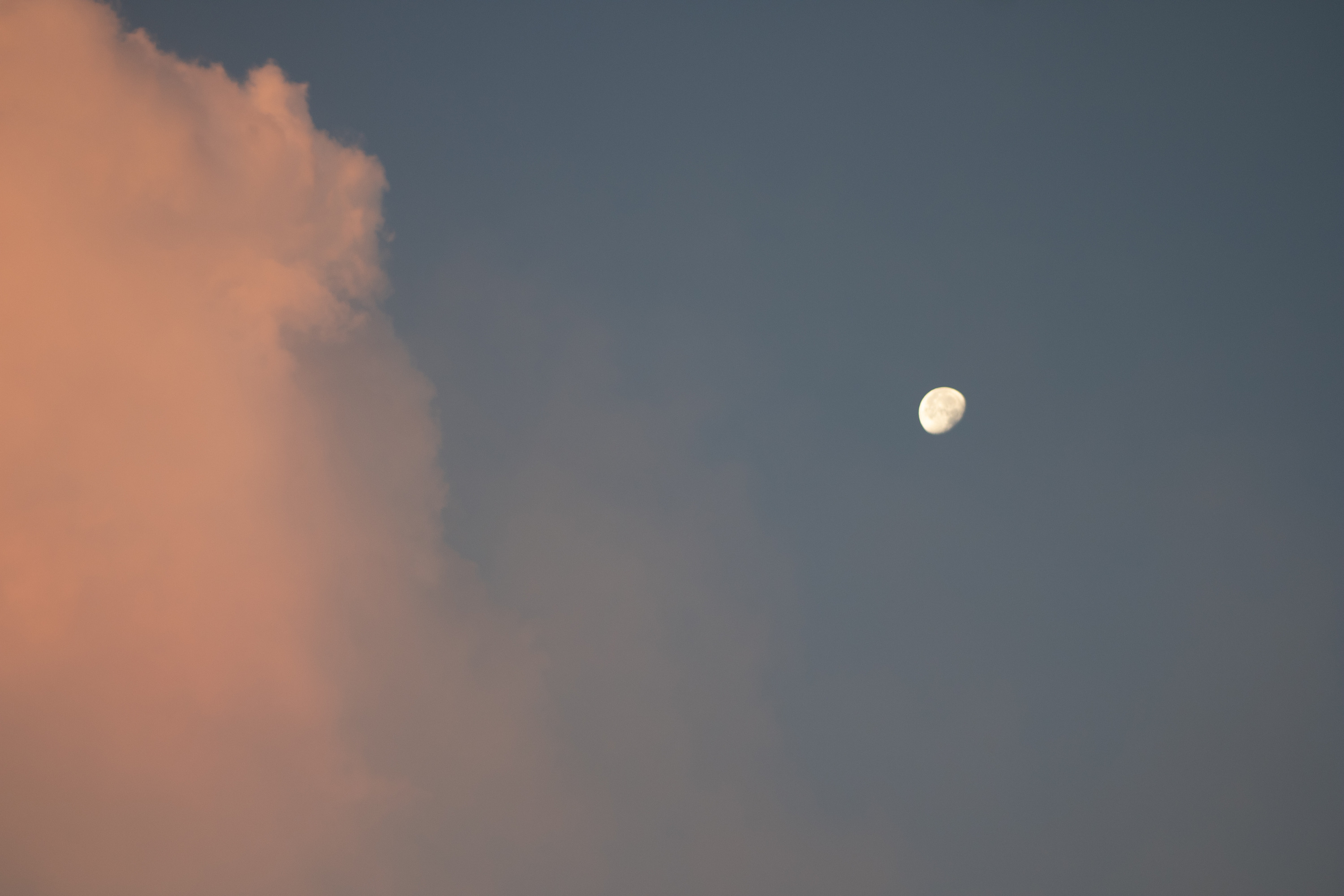 A large moon and clouds at sunrise. 