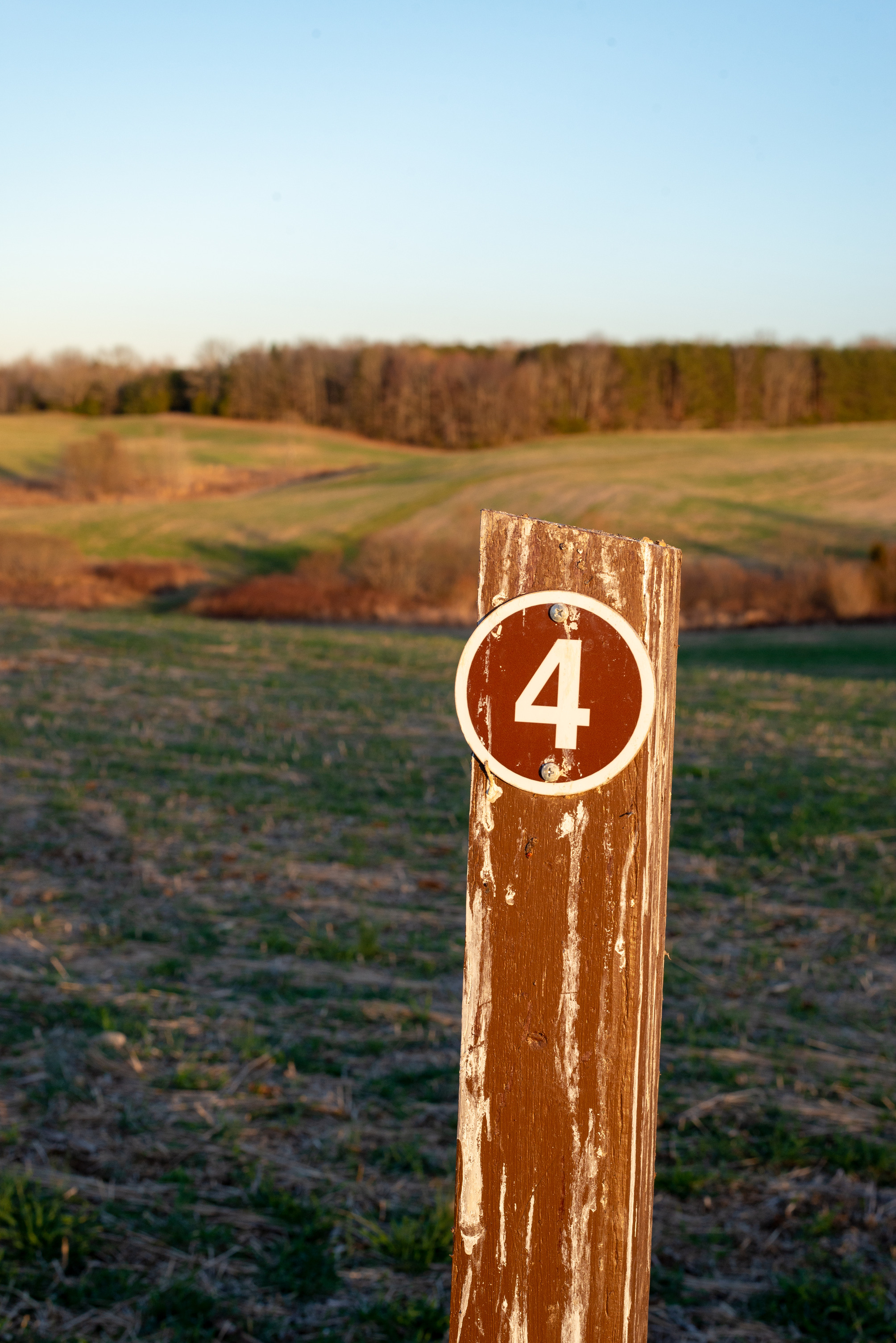 A sign with number 4 on a post in a field with rolling hills.