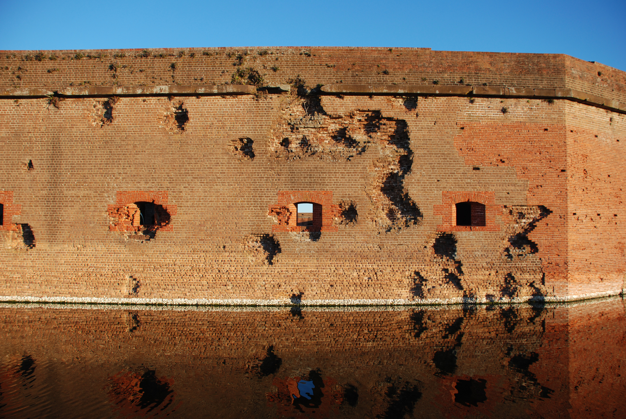An image of the south wall of Fort Pulaski showing rifled artillery damage. The precision of the rifled cannon can be seen in the damge the goes up and over the second opening from the right. There is in fact a projectile imbedded in the wall at the left corner of the "seven" shaped damage.