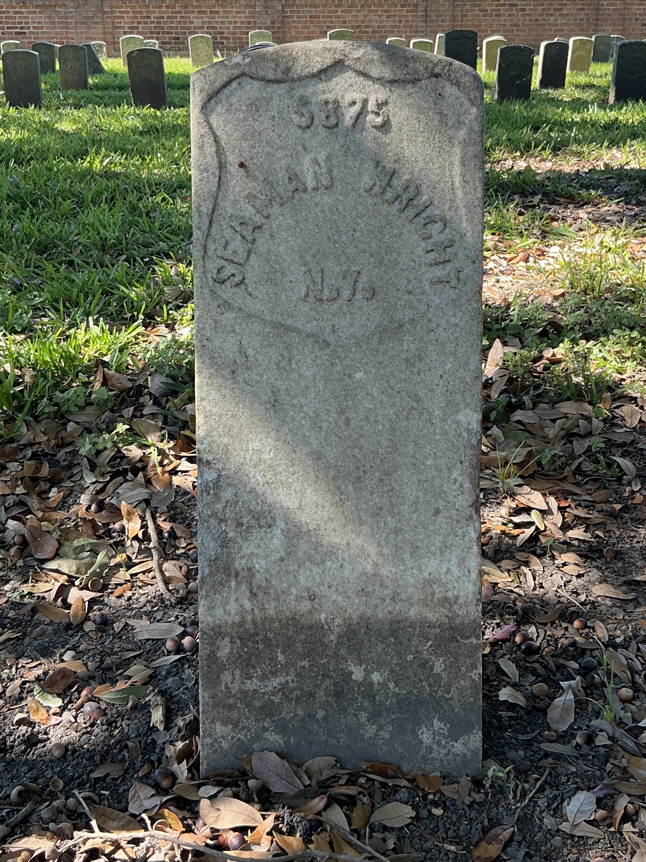 Front of historic upright marble headstone with recessed shield face.