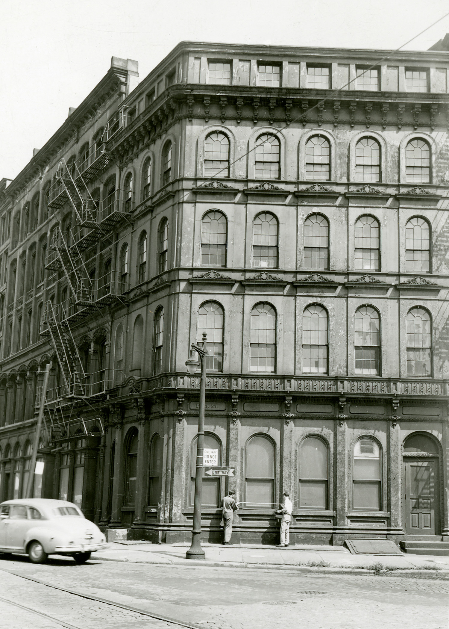 Corner view of cast iron building with semi-circle windows.