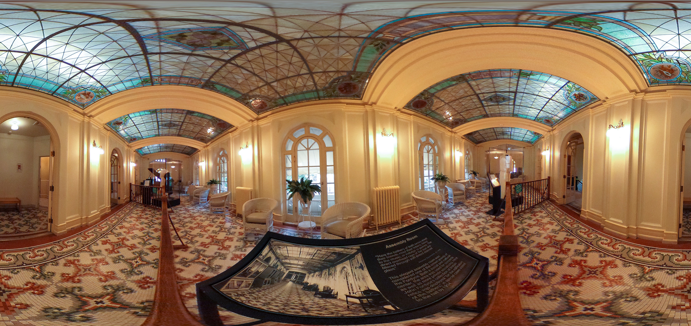 A long hallway decorated with tile flooring and a stained glass ceiling 