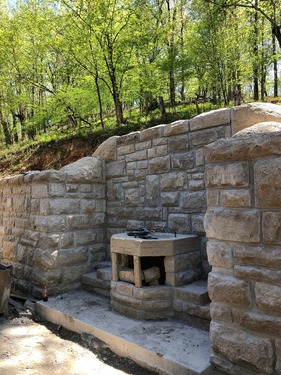 A rustic stone fountain against a stone wall.