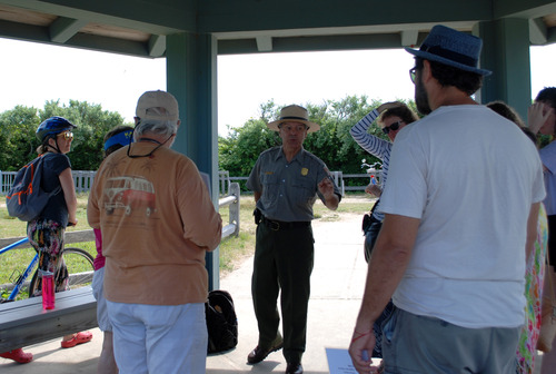 A group of visitors sand around a park ranger