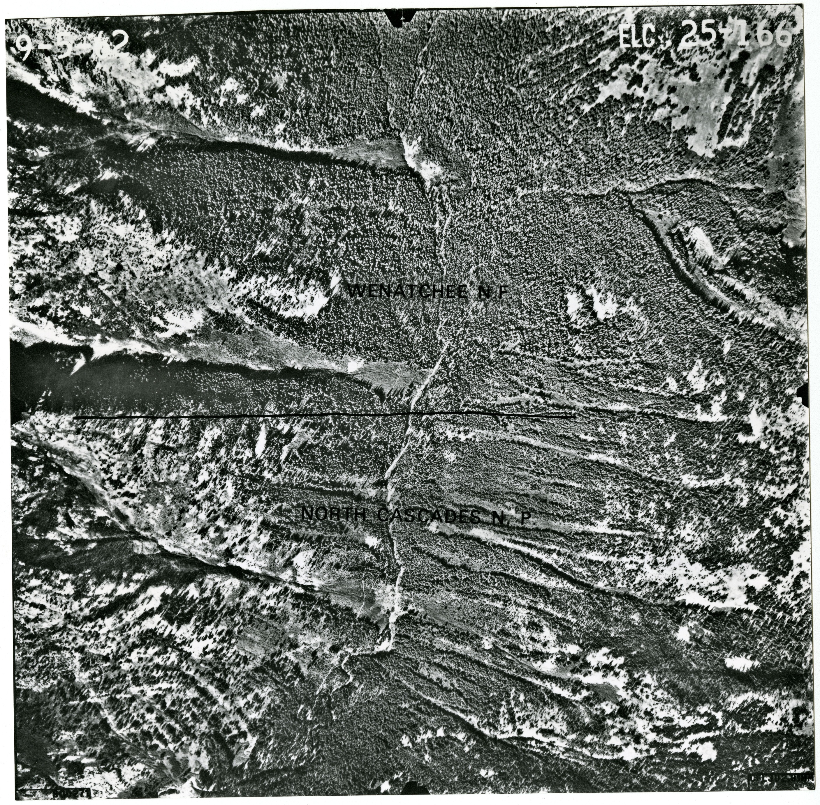 Black and white aerial photograph of glaciated mountain peaks and valleys.