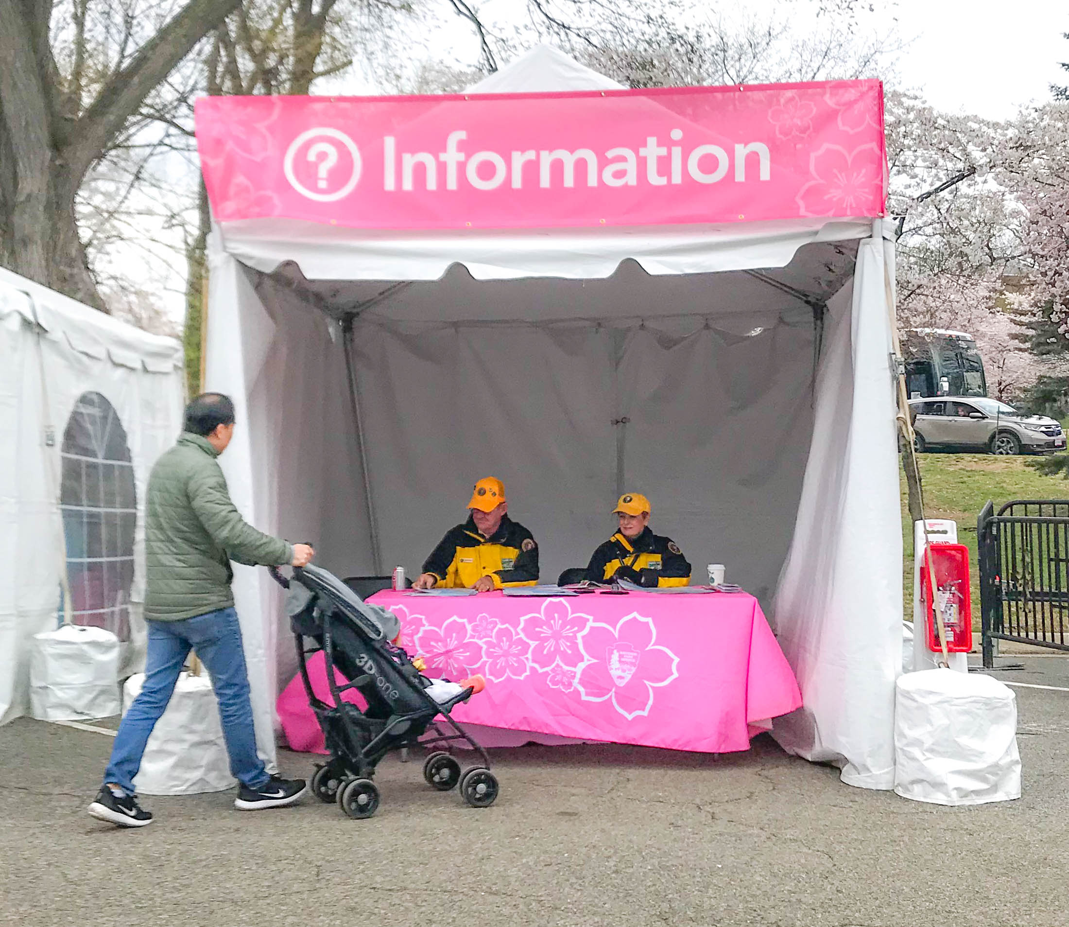 Visitor with a stroller approaching volunteers at an information tent