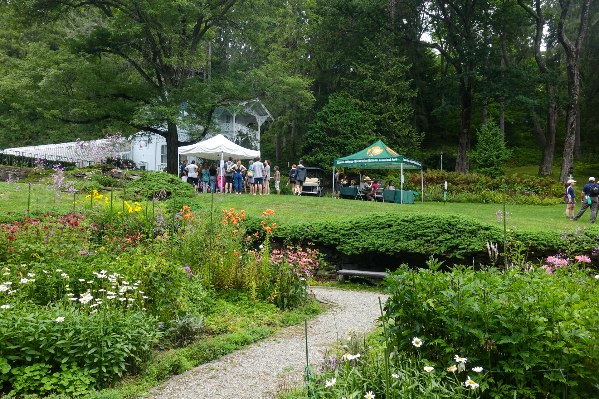 Photo taken from formal garden with canopy pop up tents in the background and visitors walking around