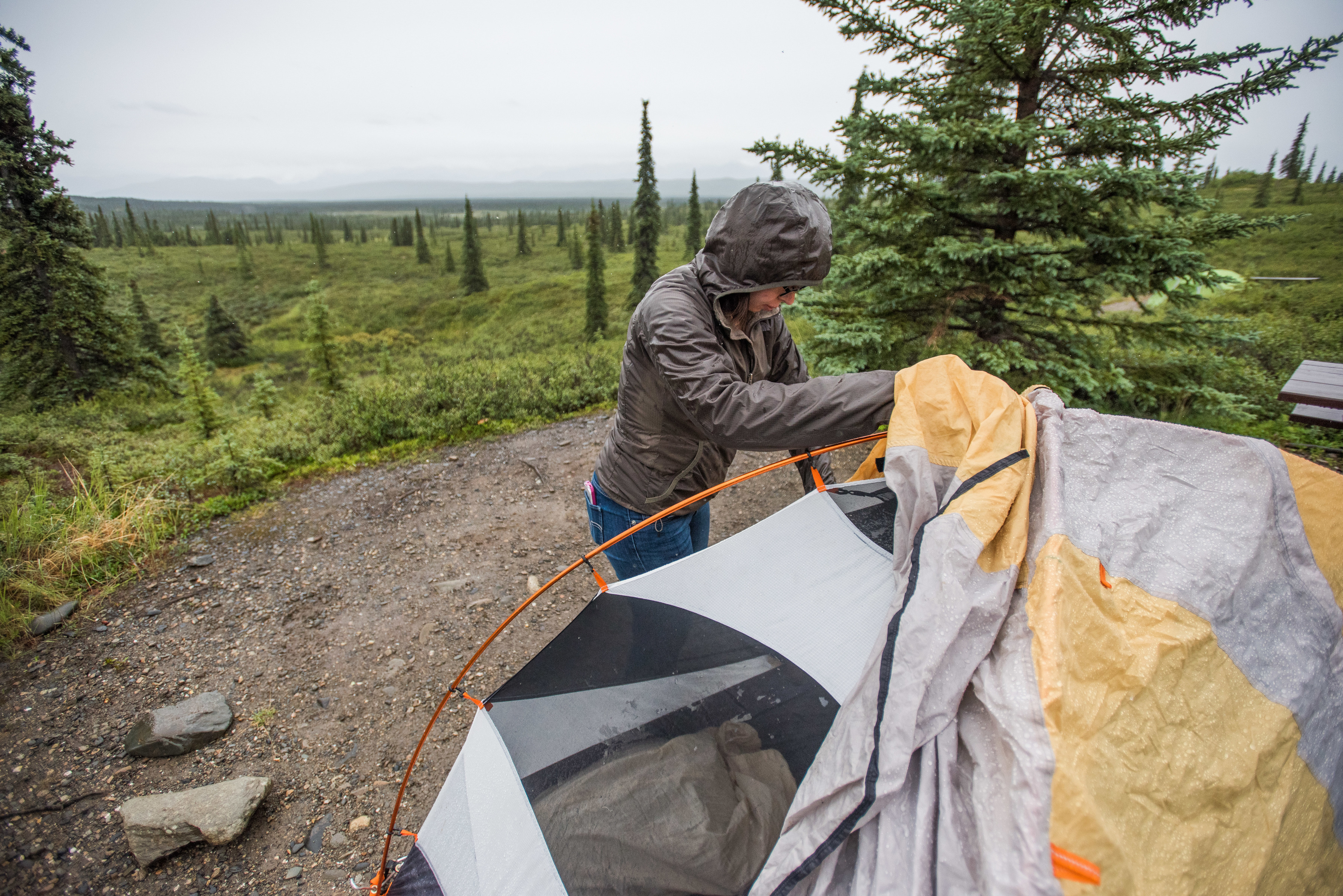woman attaching a rain fly to a tent