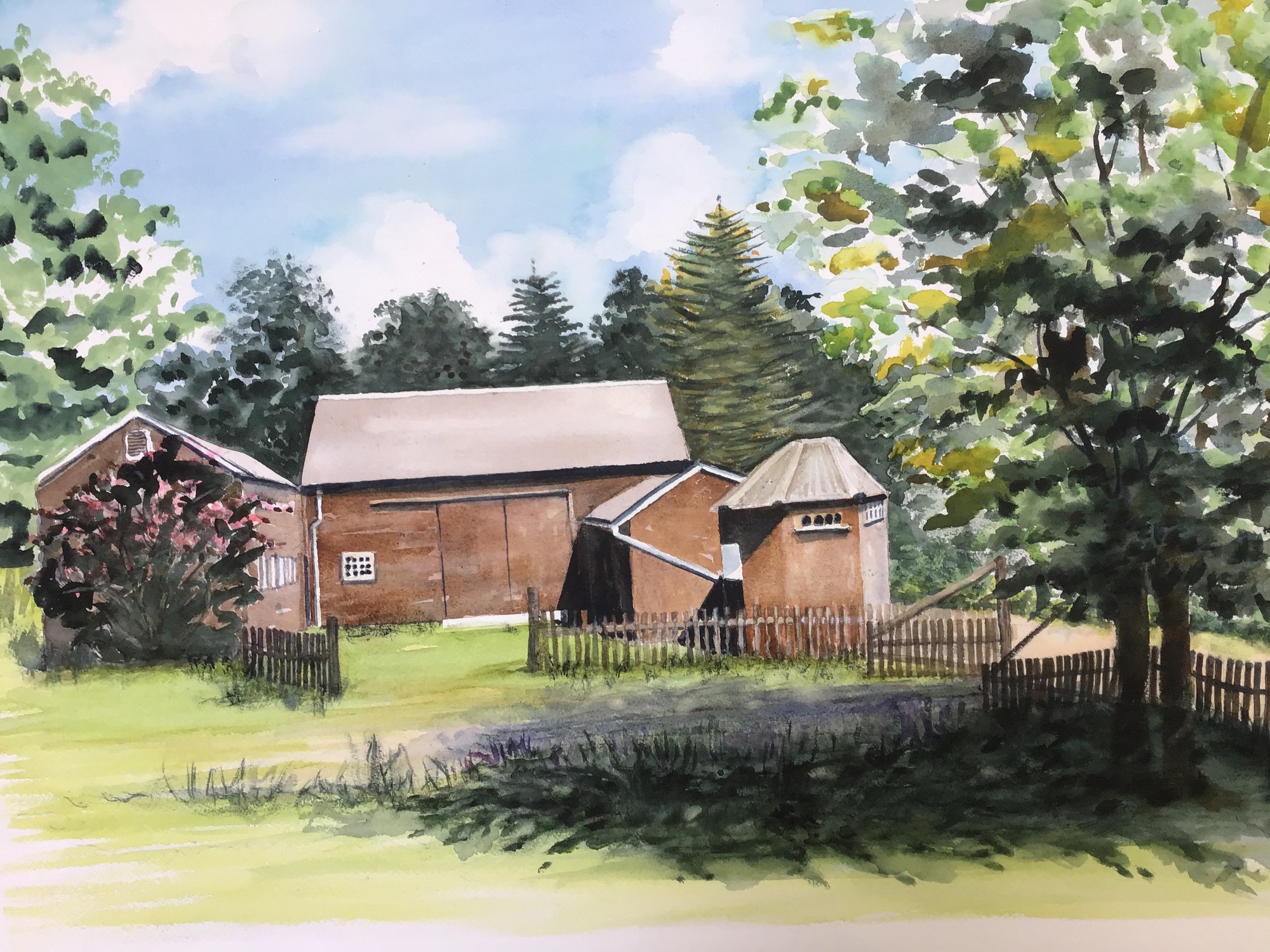 A brown barn with a fence line around it.