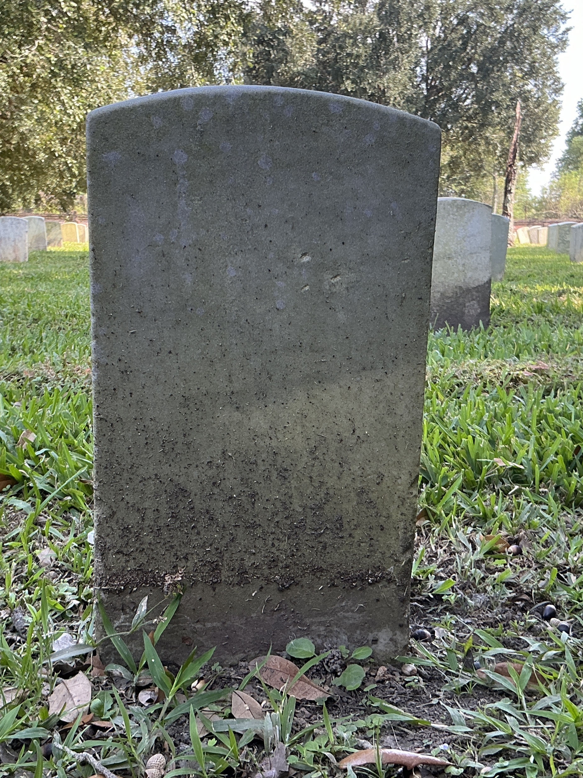 Back of historic upright marble headstone with recessed shield with recessed lettering face.