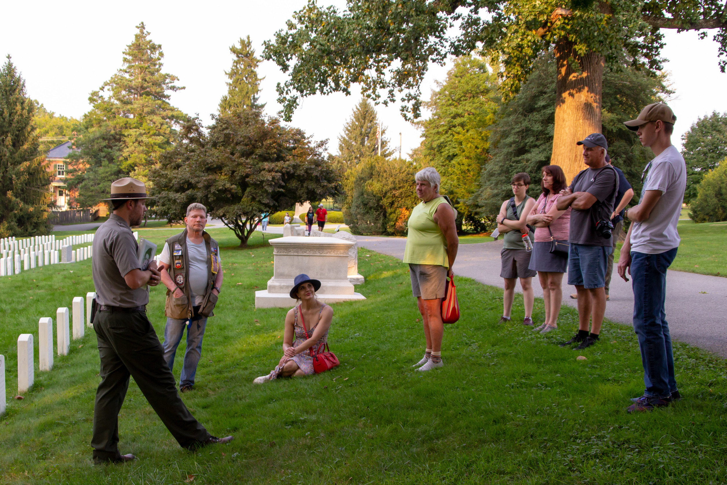 A park ranger speaks to a group of people in a military cemetery.