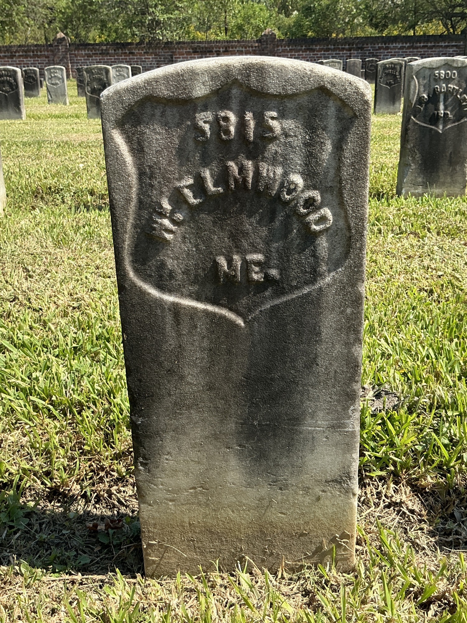 Front of historic upright marble headstone with recessed shield face.