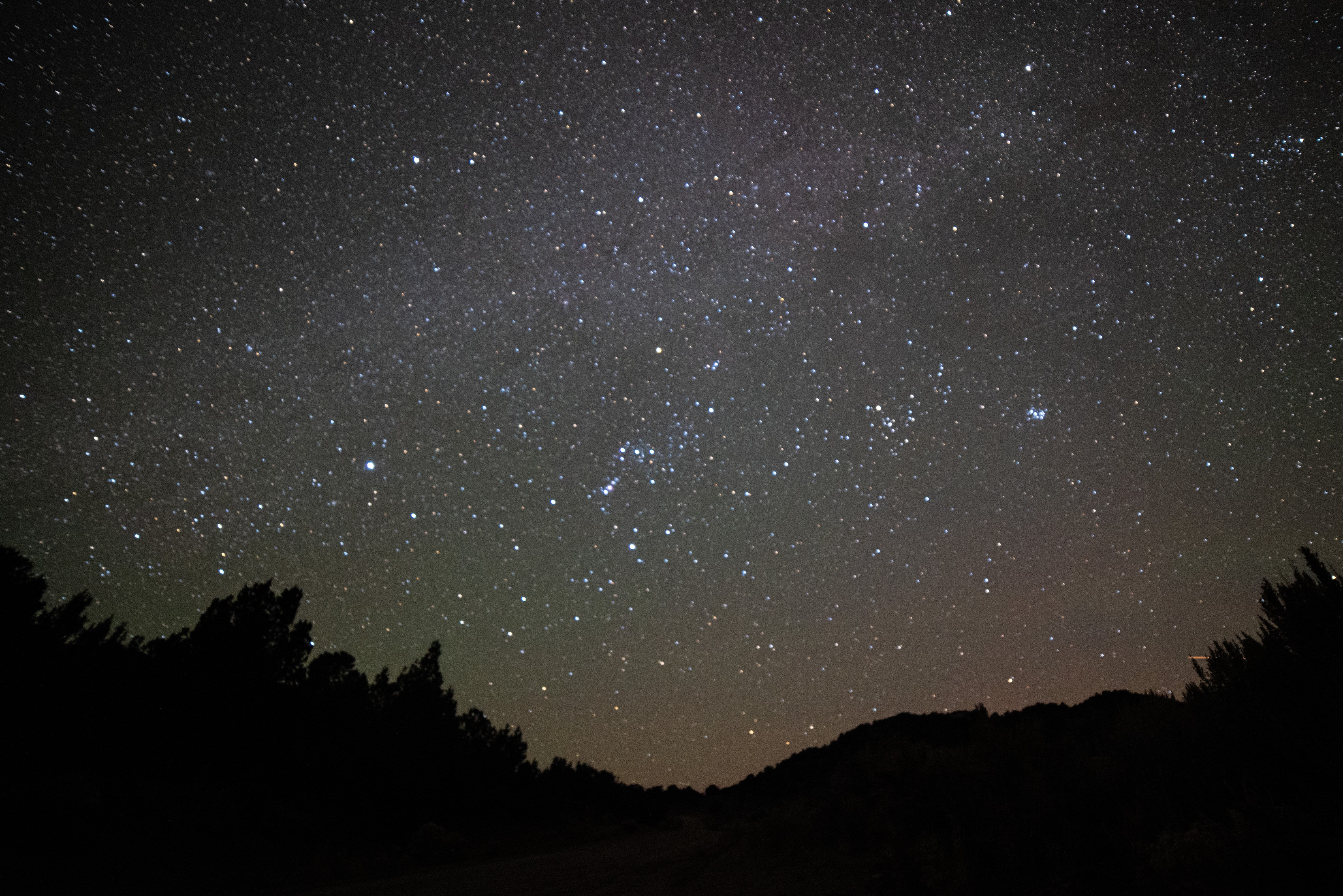 Dark silhouette of the horizon line below a dark star-filled sky.