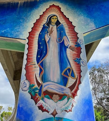 A colorful mural of the Virgin Mary painted on a freeway underpass
