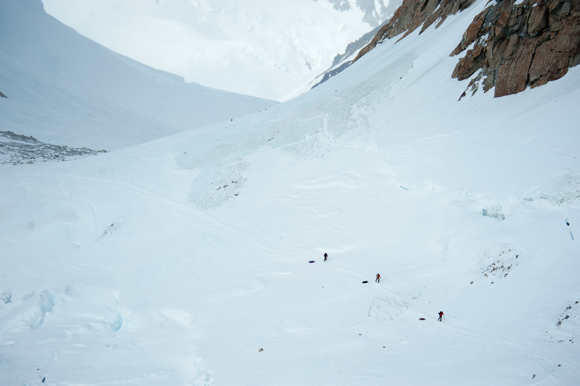 three people climbing a steep mountain slope