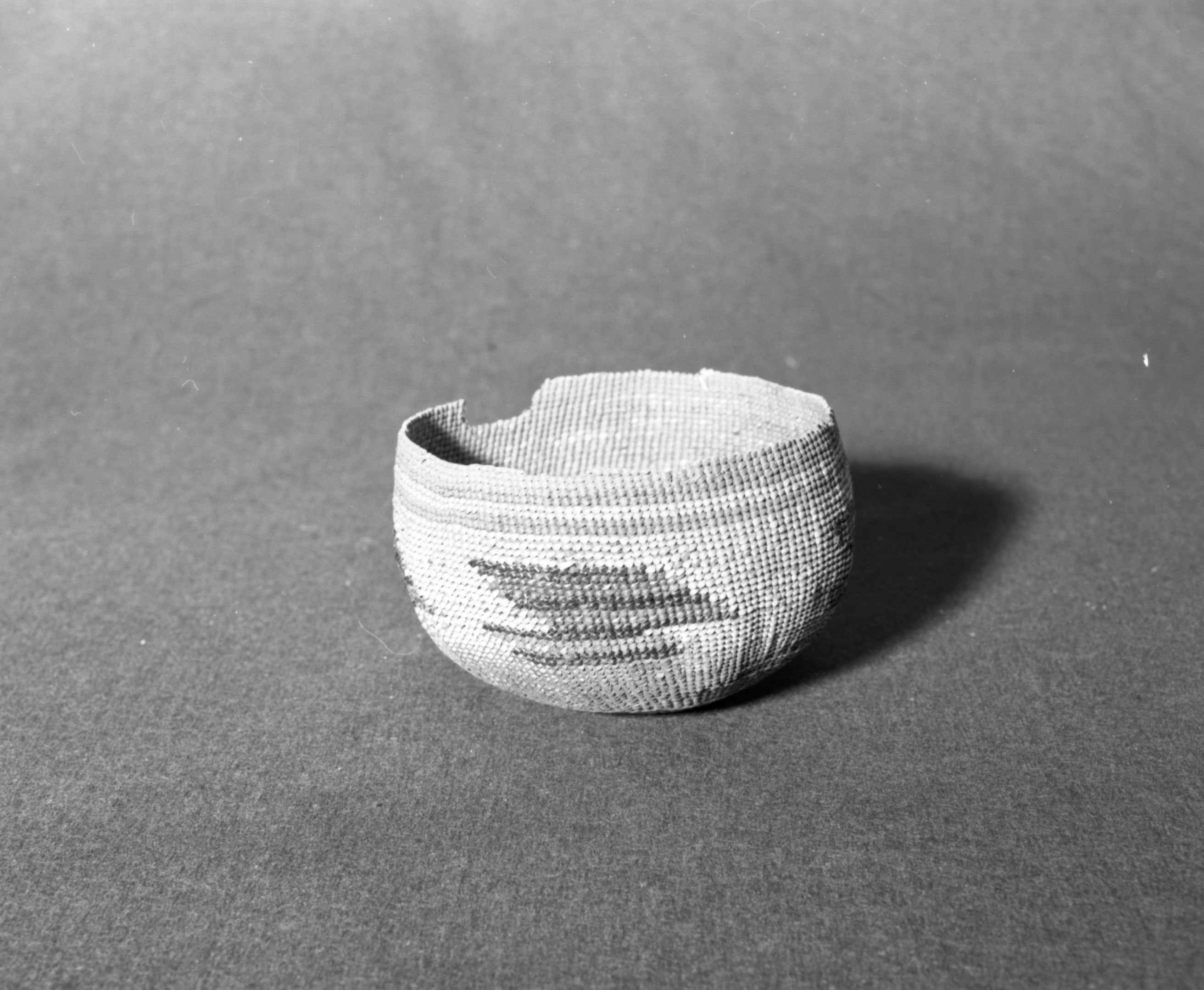 Marie Rozier Collection, Catalog No. 133. Object: Northwestern California basket. Dimensions: 6 x 4-1/8". Materials: Conifer root; beargrass; maidenhair fern stem; alder bark-dyed woodwardia fern stem. Technology: Up to right slant of turns, three strand twined start. Collection History: Gift of Ora Doyle. Appears to be mate to 134. Photographed by Michael Dixon in December 1982. Catalogued by Craig Bates and Barbara Beroza. Yosemite Collections, National Park Service.