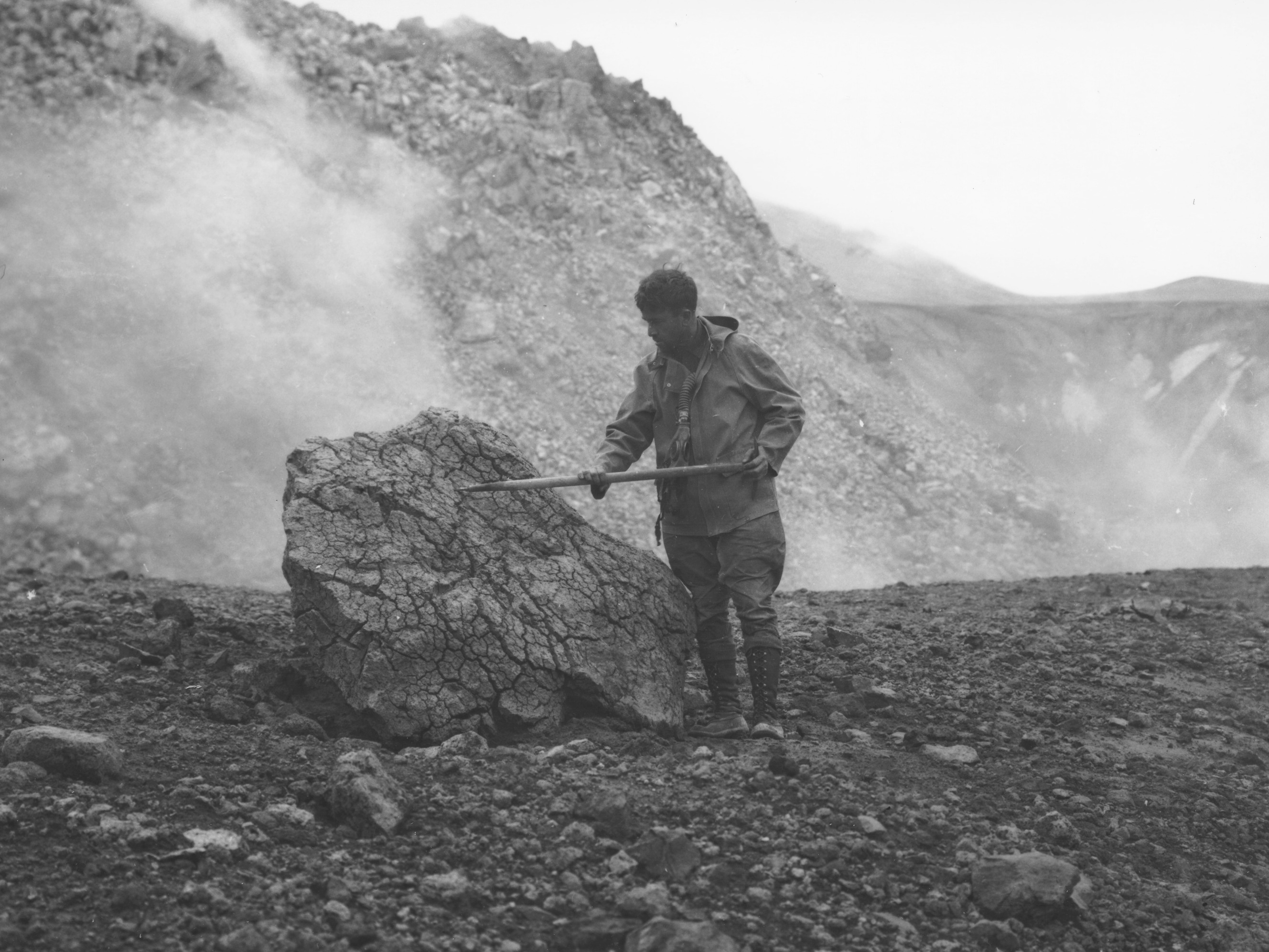 Photograph of Bernard Hubbard inspecting a bread-crust bomb adjacent to the steaming Novarupta dome in 1935. 