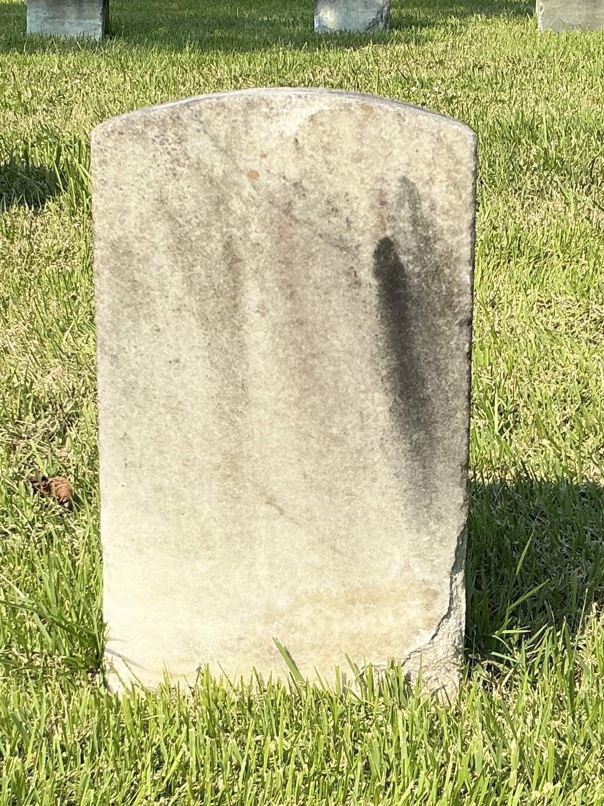 Back of historic upright marble headstone with recessed shield face.