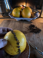 An orange with a line of cloves inserted into its peel.