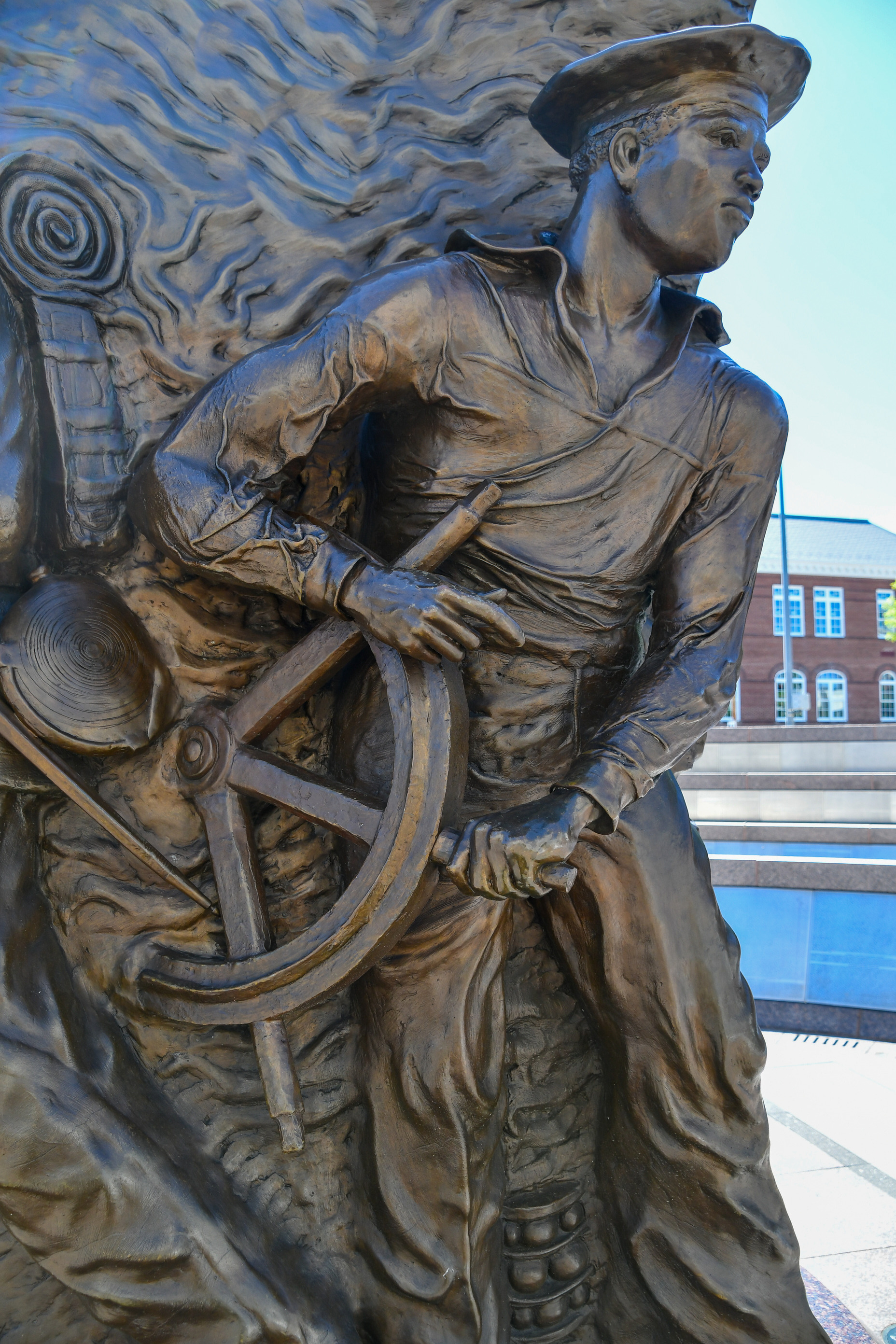 A broze statue depicts a African American sailor holding a ship's helm